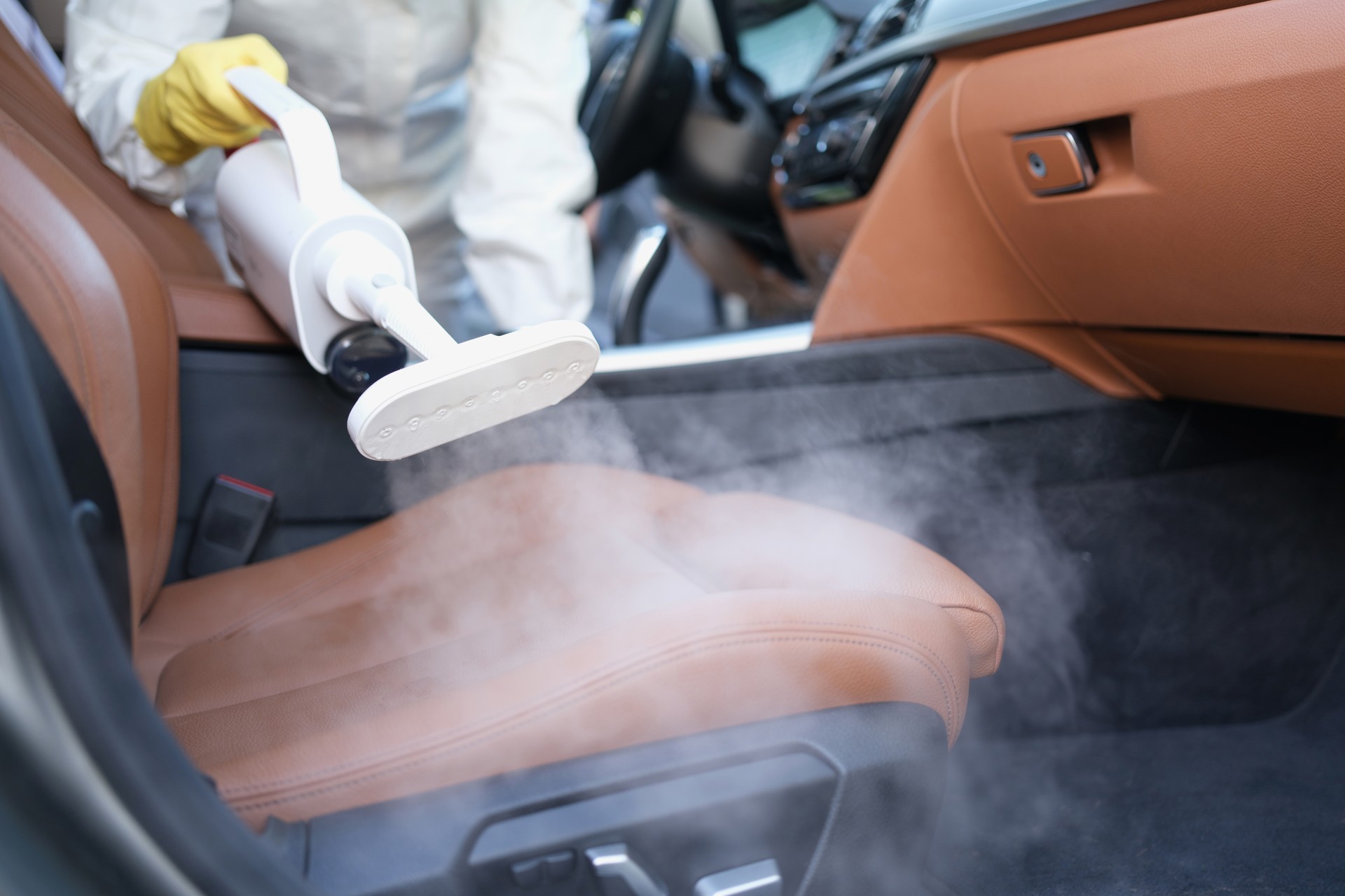 Cleaner disinfecting car interior with steamer closeup