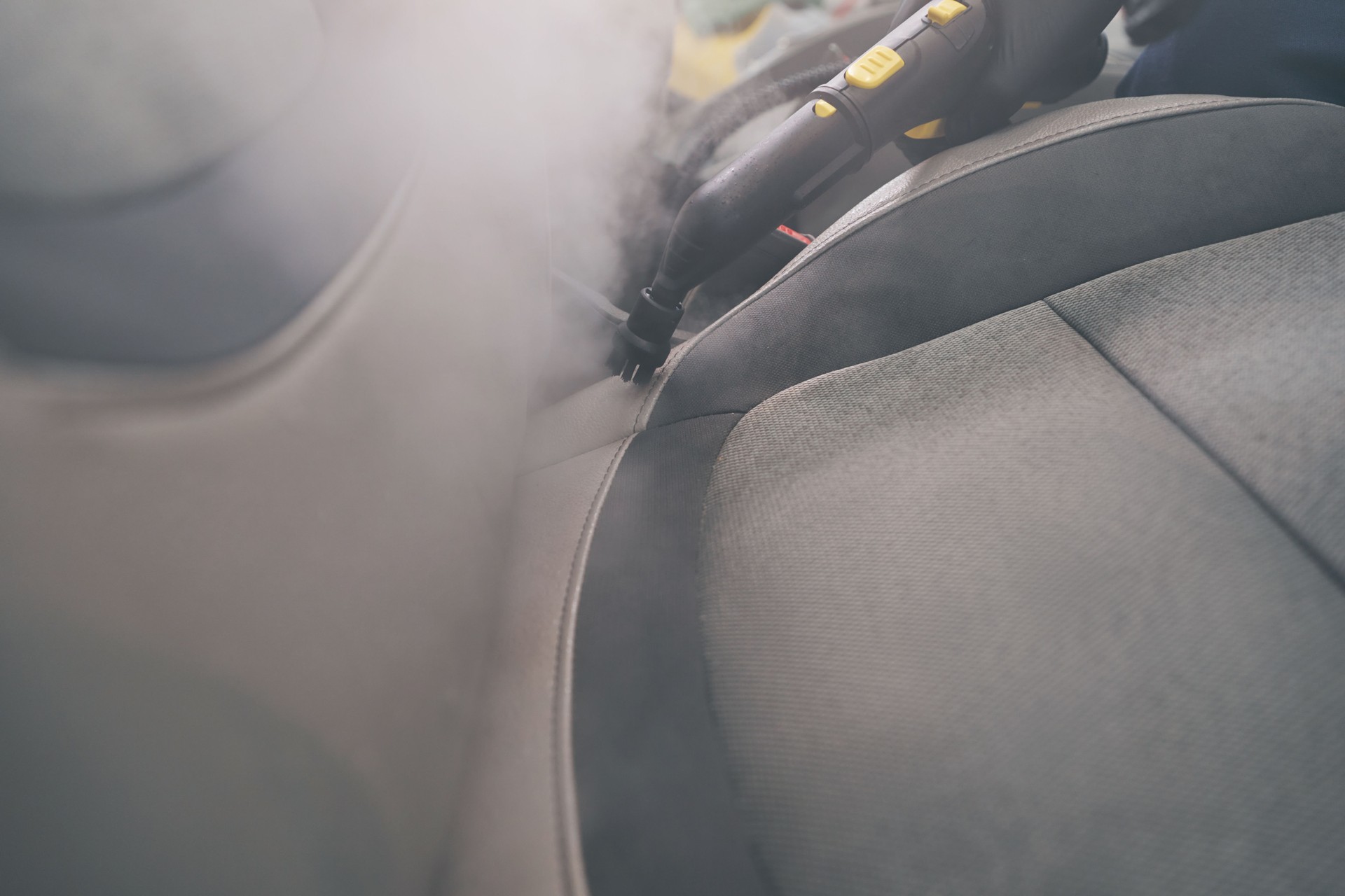 Steam cleaning close-up in auto detailing. Car seats wash with steamer